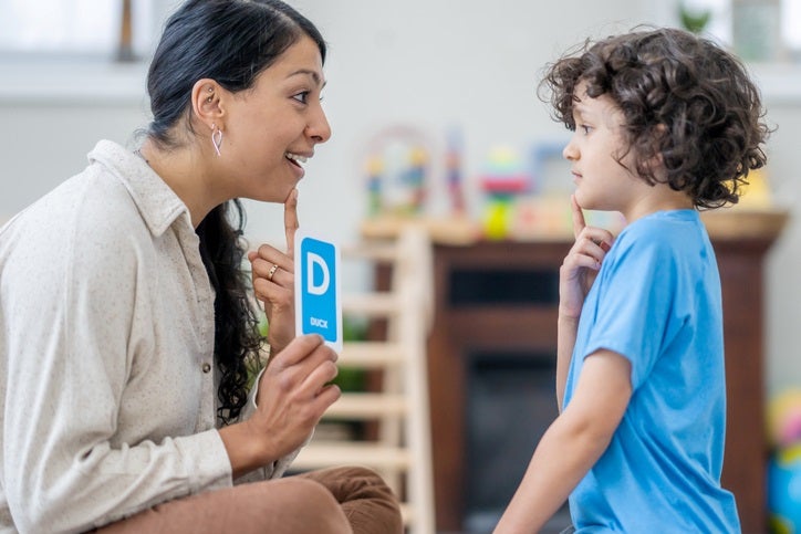 The therapist is teaching the child sounds using a letter card in Houston, TX