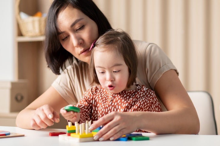 Mother helping child stack colorful wooden shapes in Houston, TX